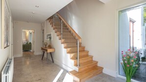 A modern interior with a wooden staircase, a hallway leading to a bedroom, and a view of the outdoors.