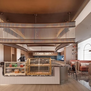 A modern interior with a central counter, seating area, and a staircase.