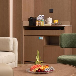 A compact kitchenette with a coffee machine, bottles, and a kettle on the countertop.