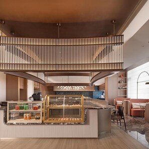 A modern interior with a central counter, seating area, and a staircase.