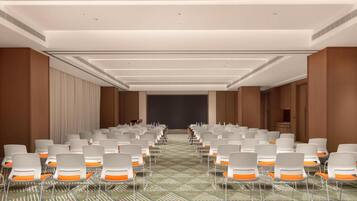 A conference room with rows of chairs, a projector screen, and a carpeted floor.