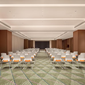 A conference room with rows of chairs, a projector screen, and a carpeted floor.