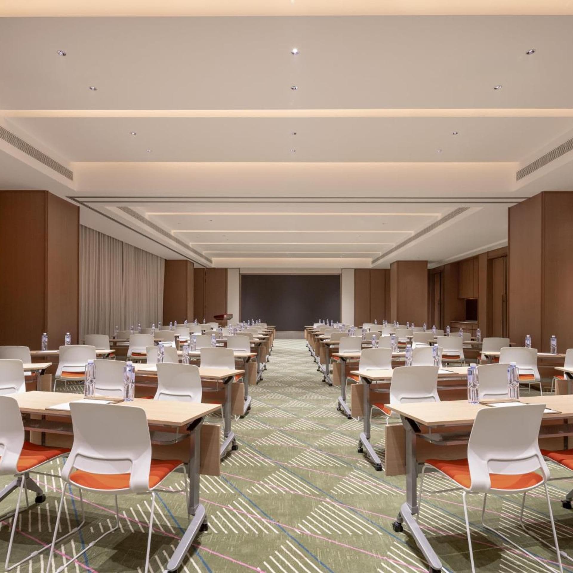 A conference room with rows of tables and chairs, equipped with water bottles and nameplates.