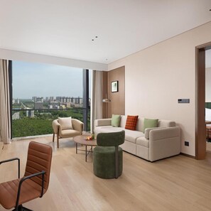 A modern living room with a sofa, armchairs, a coffee table, and a view of the cityscape.