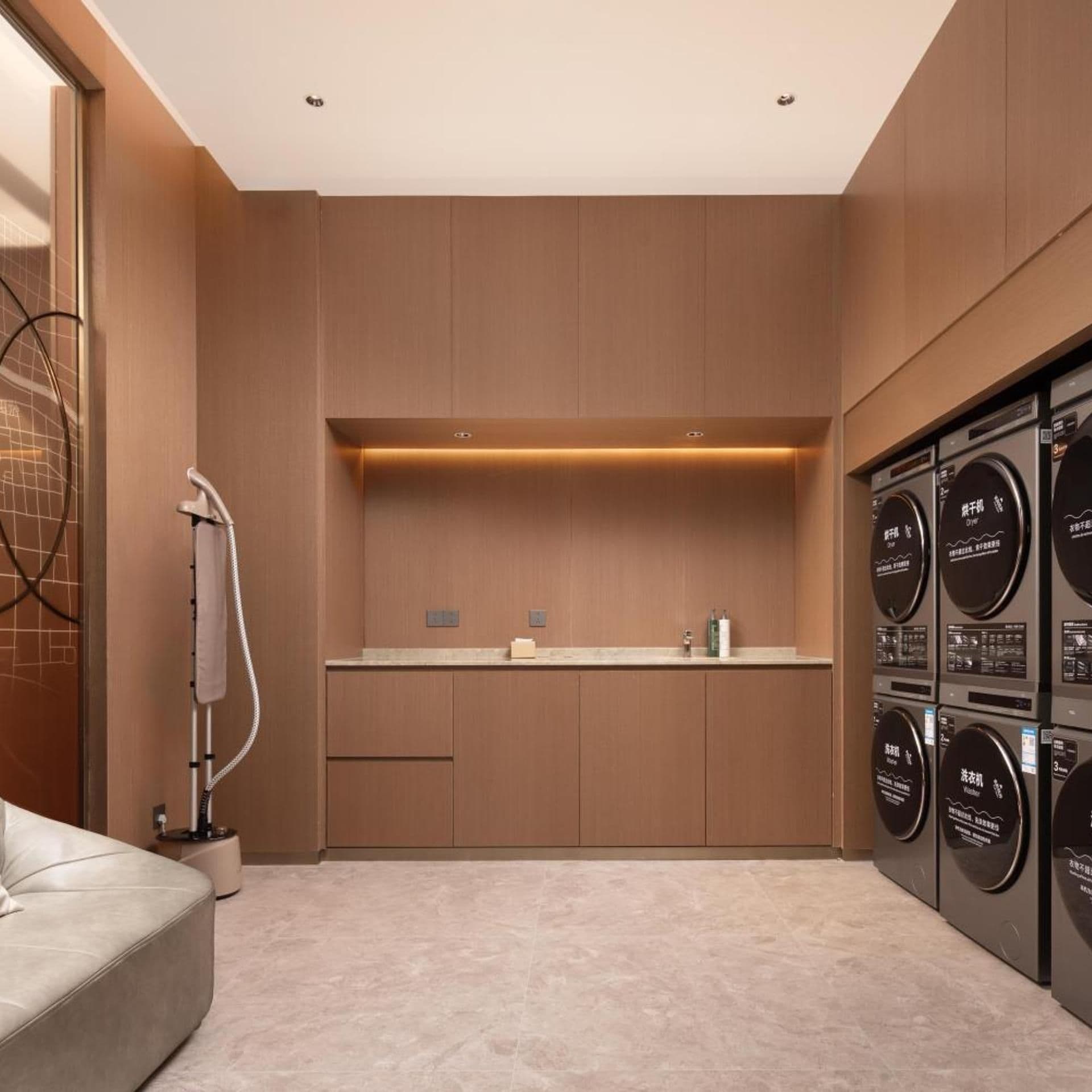 A modern laundry room with a built-in washing machine and dryer, a towel rack, and a small countertop.