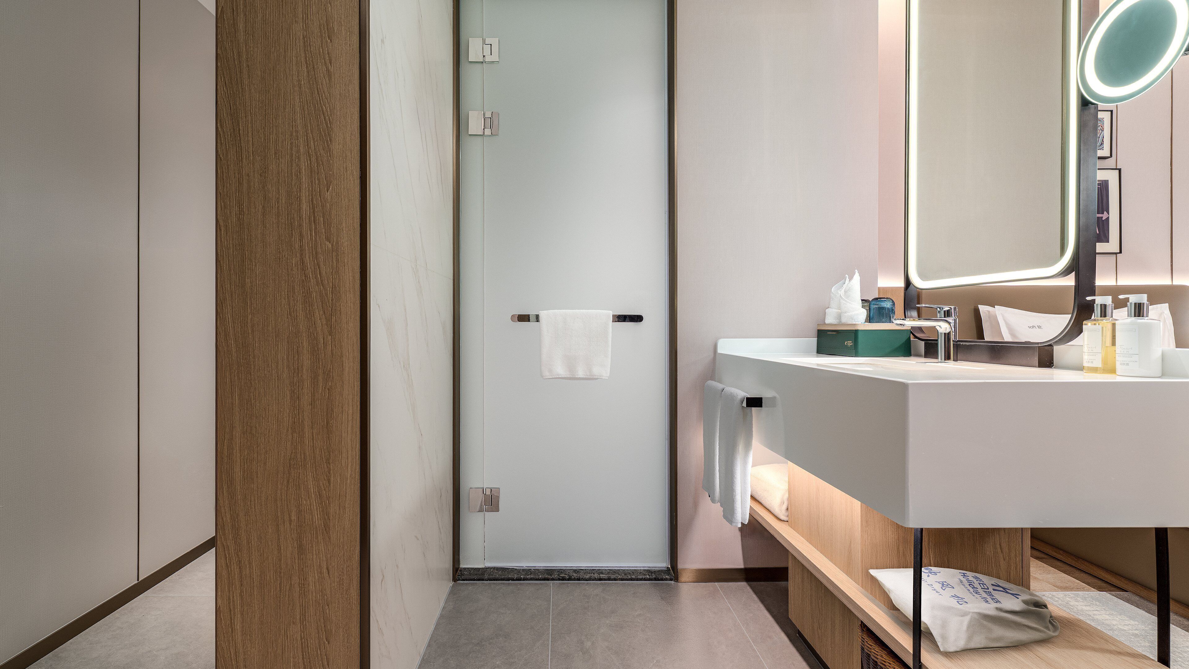 A modern bathroom with a white sink, mirror, and towel rack.
