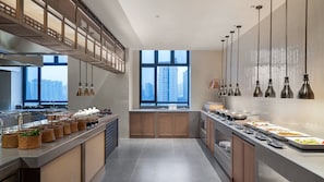 Een moderne keuken met een lange aanrecht, hangende lampen en uitzicht op hoge gebouwen.