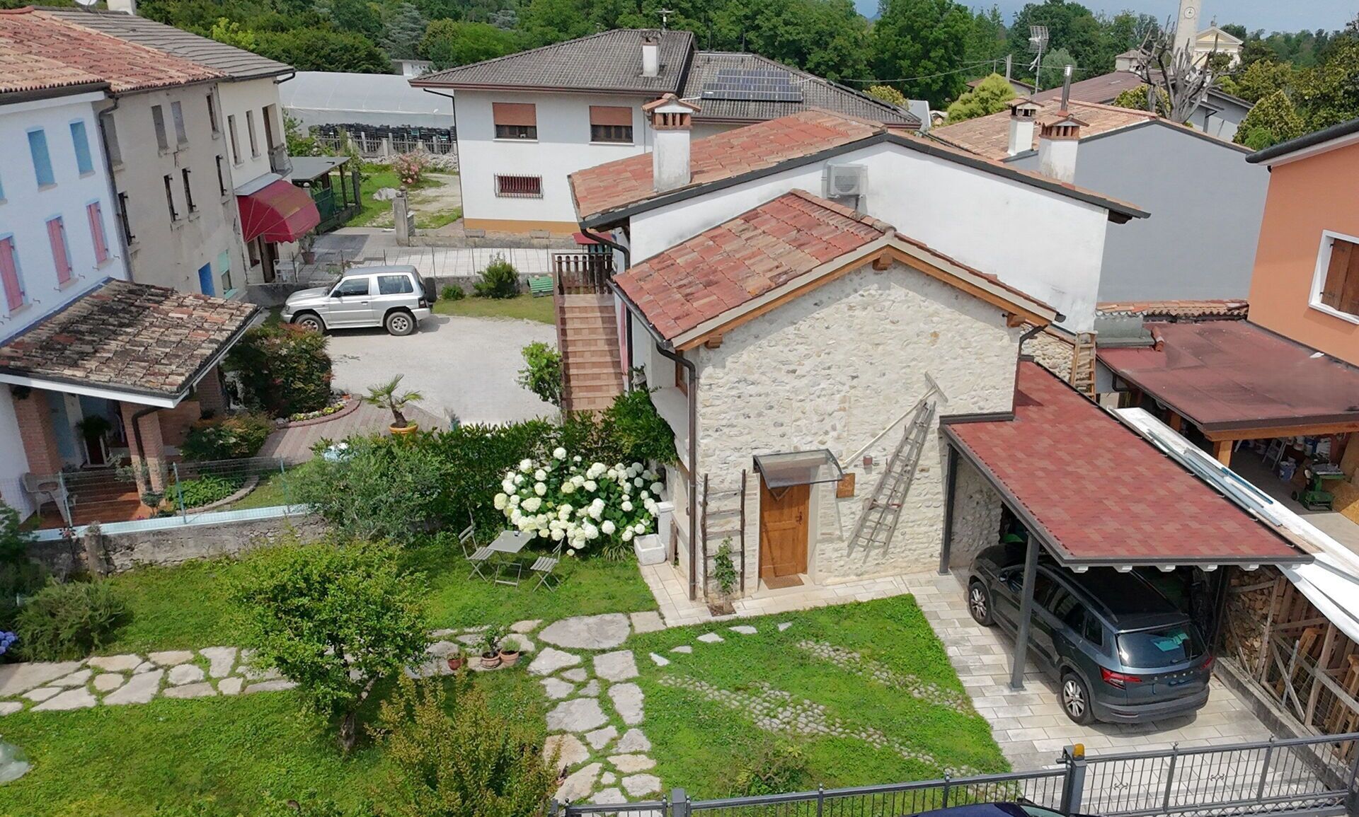 A residential area with stone buildings, a paved driveway, and a car parked in front.