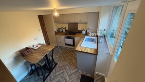 Een compacte keuken met een visgraatvloer, een houten eettafel en een raam met uitzicht.
