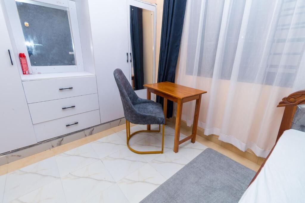 A bedroom with a bed, a desk, a chair, a wardrobe, and a window.