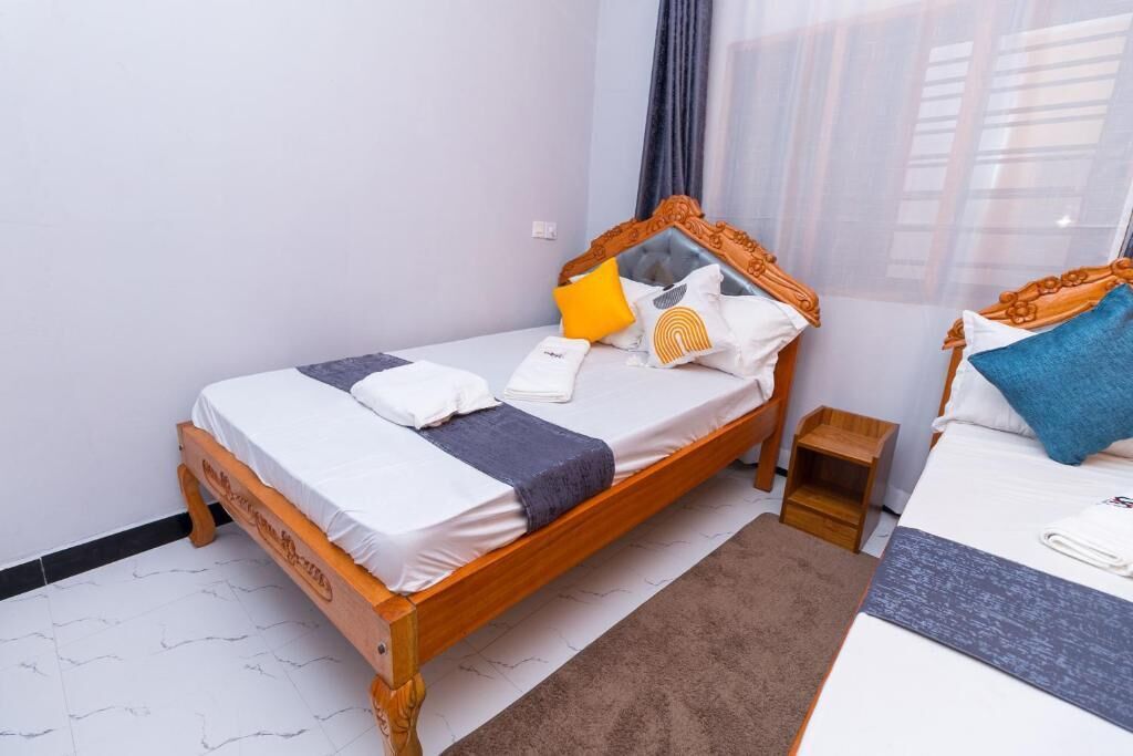 A single bed with a wooden frame, white bedding, and multiple pillows.