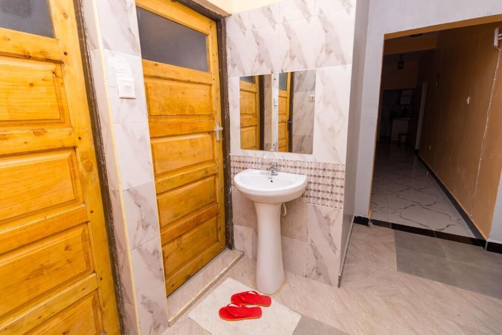 A bathroom with a wooden door, a white sink, and a mirror.