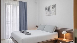 Et moderne hotelværelse med en stor seng, et natbord med lampe, og et kunstværk på væggen.