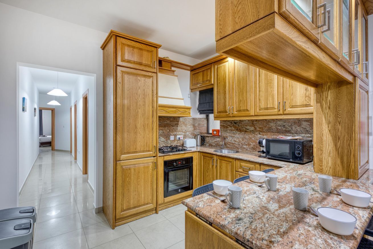 A kitchen with wooden cabinets, granite countertops, a microwave, and a stove.