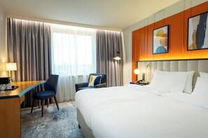 A hotel room with a bed, two chairs, a desk, a lamp, and a window with curtains. - Voco Dusseldorf Seestern An Ihg Hotel (Düsseldorf)