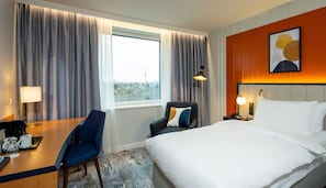 A hotel room with a bed, a desk with a chair, a telephone, and a window with curtains. - Voco Dusseldorf Seestern An Ihg Hotel (Düsseldorf)