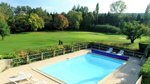A swimming pool with lounge chairs and a view of a golf course.