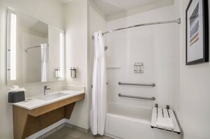 Un baño moderno con lavamanos, espejo y zona de ducha blanca.