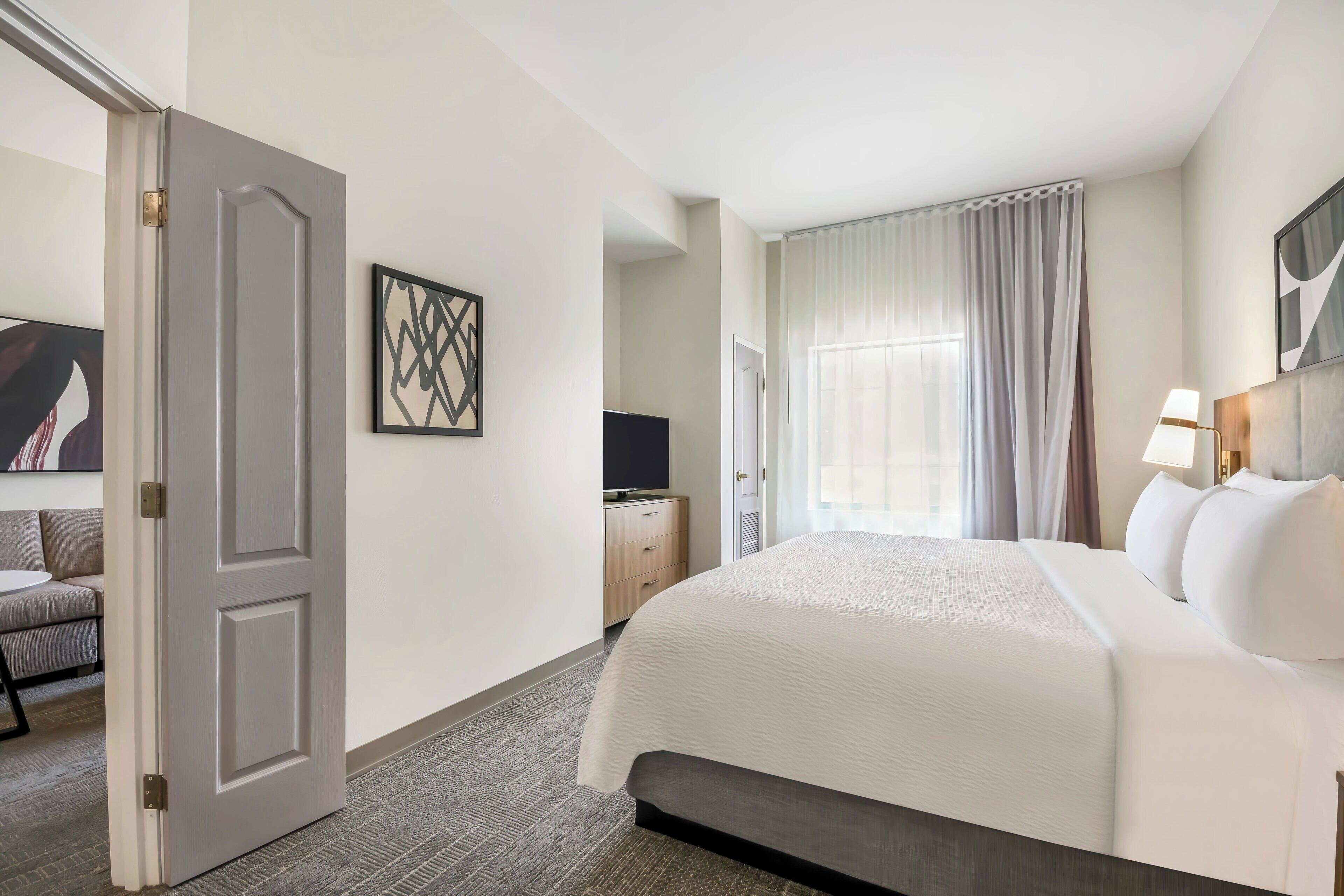 A hotel room with a bed, a television, a desk, and a door.