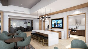 Een moderne keuken met een groot eiland, barkrukken en een televisie.