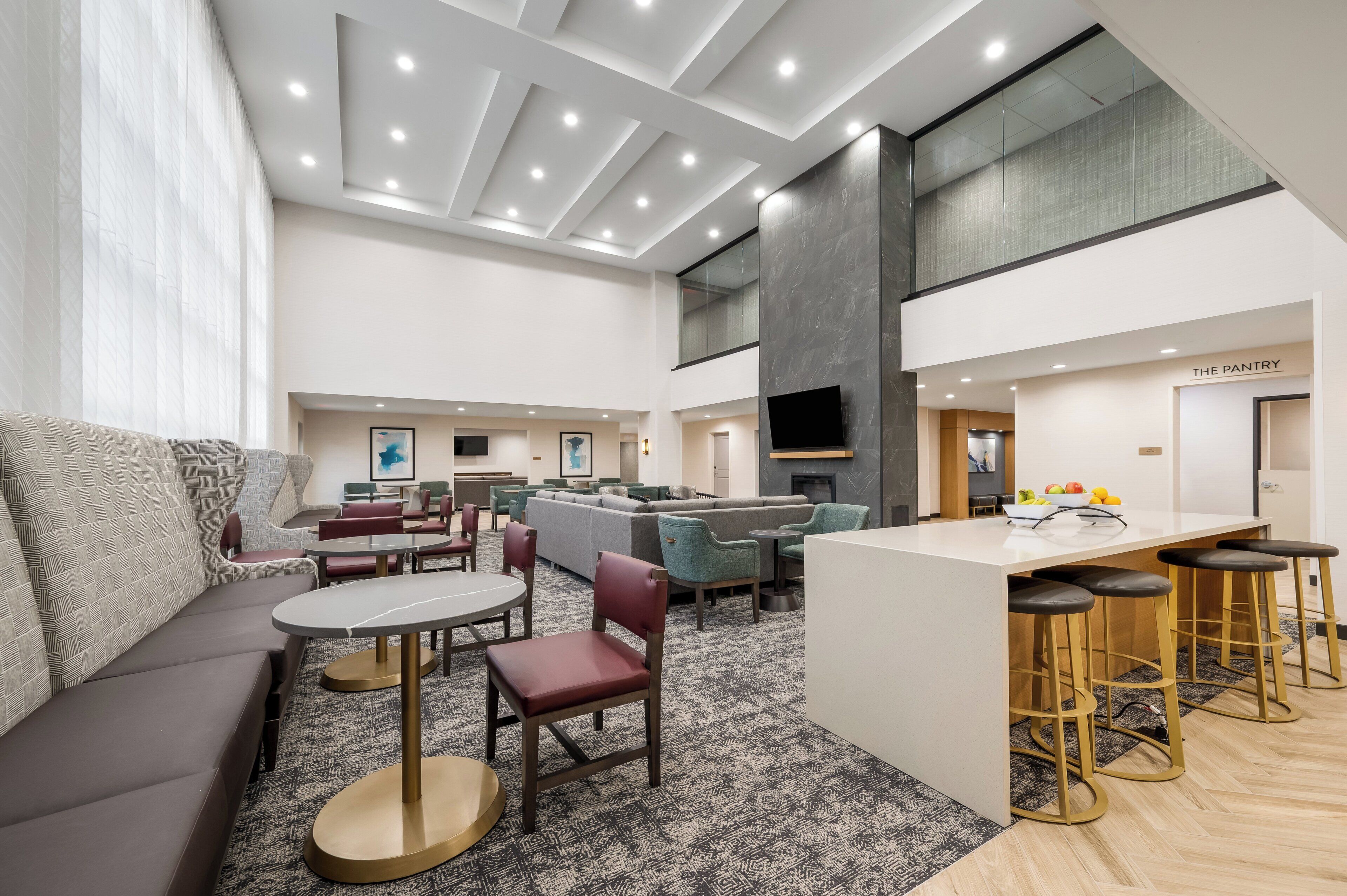 Un vestíbulo de hotel moderno con zona de estar, bar y kitchenette.