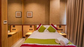 Une chambre d’hôtel avec un grand lit, deux tables de chevet, un miroir et un téléphone fixé au mur.