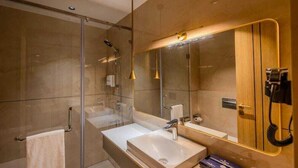 Une salle de bain moderne avec une douche à l’italienne en verre, un grand miroir et un téléphone.