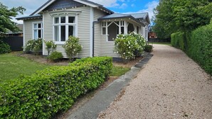Yhden kerroksen talo, jossa on kuisti, sorapäällysteinen ajotie ja hyvin hoidettu nurmikko.