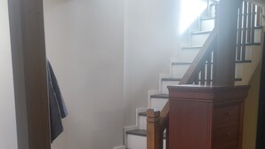 A staircase with wooden handrails and a brick base, leading to an upper floor.