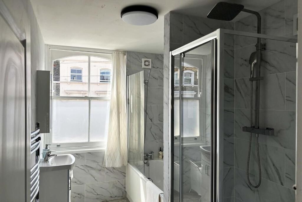 A modern bathroom with a glass shower enclosure, a bathtub, and a vanity with a sink.