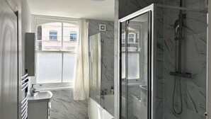 Un baño moderno con cabina de ducha de vidrio, bañera y tocador con lavabo.