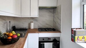 Una cocina moderna con armarios blancos, salpicadero de mármol, cocina a gas y un lavamanos.