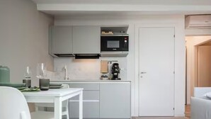 Cozinha moderna com armários brancos, micro-ondas embutido e máquina de café.
