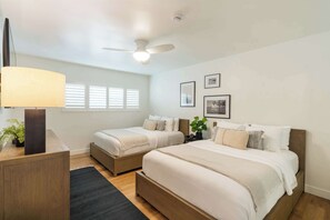 A bedroom with two beds, a ceiling fan, a lamp, and framed pictures on the wall. - Oceanview Luxe Home | Steps to the Strand | Bikes (Manhattan Beach)