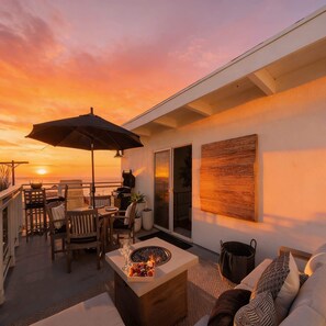 A patio with a fire pit, outdoor furniture, and a view of the sunset. - Oceanview Luxe Home | Steps to the Strand | Bikes (Manhattan Beach)