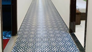 A hallway with patterned flooring, recessed ceiling lights, and doors leading to rooms. - Hotel Uday Raj (Agra)