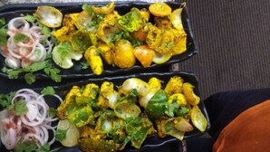 A meal with various vegetables and onions, served in a black tray. - Hotel Uday Raj (Agra)