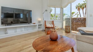 Ein modernes Wohnzimmer mit Flachbildfernseher, Holz-Couchtisch und bequemer Couch.