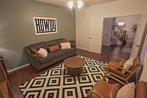 Ein Wohnzimmer mit grauem Sofa, Teppich mit Muster und Couchtisch aus Holz.