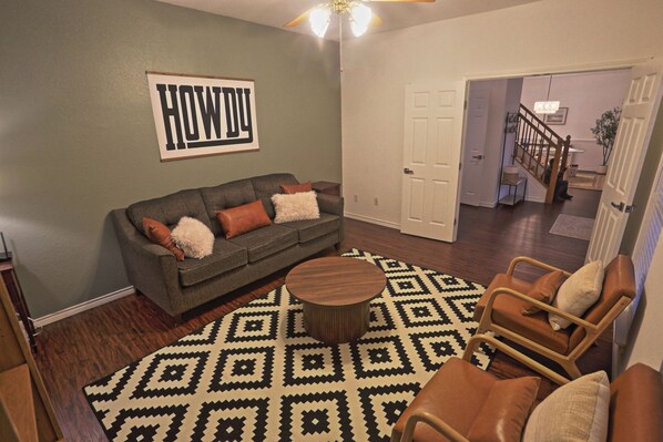 A living room with a grey sofa, patterned rug, and a wooden coffee table.