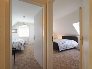 Een slaapkamer met een bed, een stoel, een radiator, een raam met zonwering en een plafondlamp.