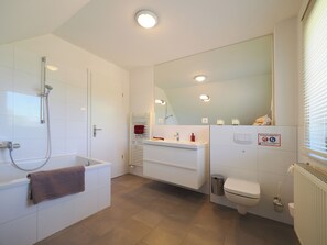 Een moderne badkamer met een bad, toilet en wastafel.