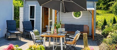 An outdoor patio with a table, chairs, and an umbrella.