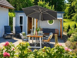 Een terras buiten met een tafel, stoelen en een parasol.