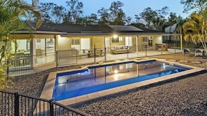 Une maison moderne dotée d’une piscine, d’un espace salon extérieur et d’une terrasse clôturée.