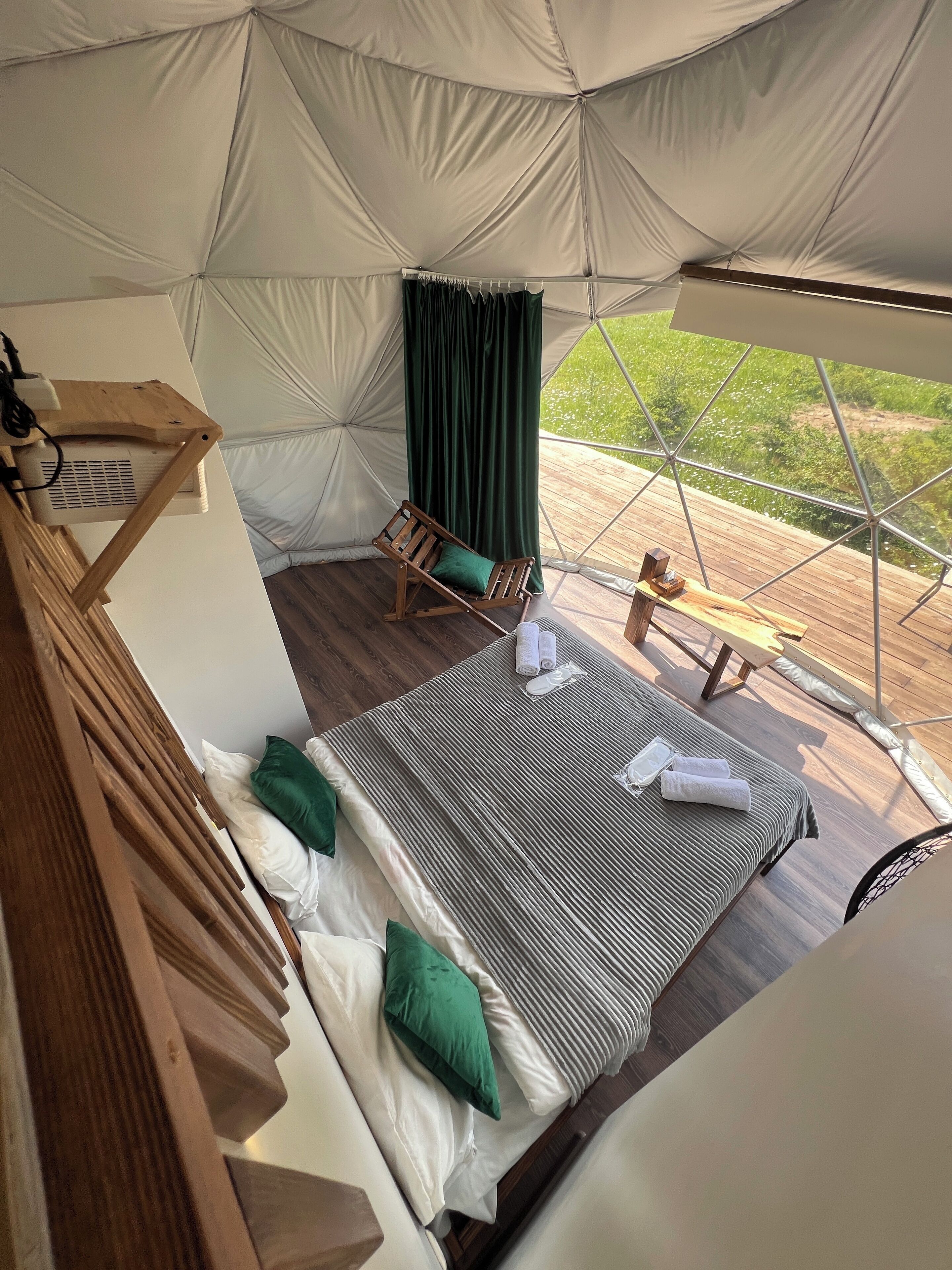 Alojamiento con tienda de campaña, una cama, una mecedora de madera y vistas al follaje exterior.