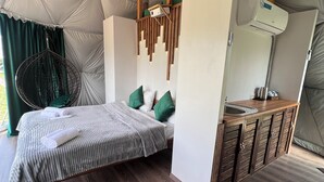 A tent-style room with a bed, hanging chair, and wooden cabinets. - GLAMPING PARK  (Shahumyan)
