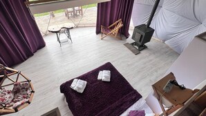 A tented accommodation with a bed, a table, a hanging chair, and a wood-burning stove. - GLAMPING PARK  (Shahumyan)