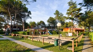 Ein Spielplatz mit Rutschen und Klettergerüsten, umgeben von Bäumen und einem Fußweg.