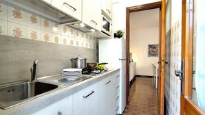 Een keuken met een RVS spoelbak, witte kastjes, een magnetron en een fornuis.